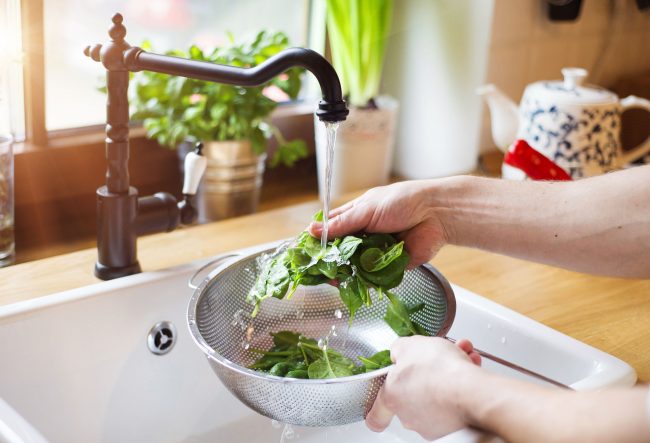 40802271 – unrecognizable man washing green salad leaves in the kitchen sink
