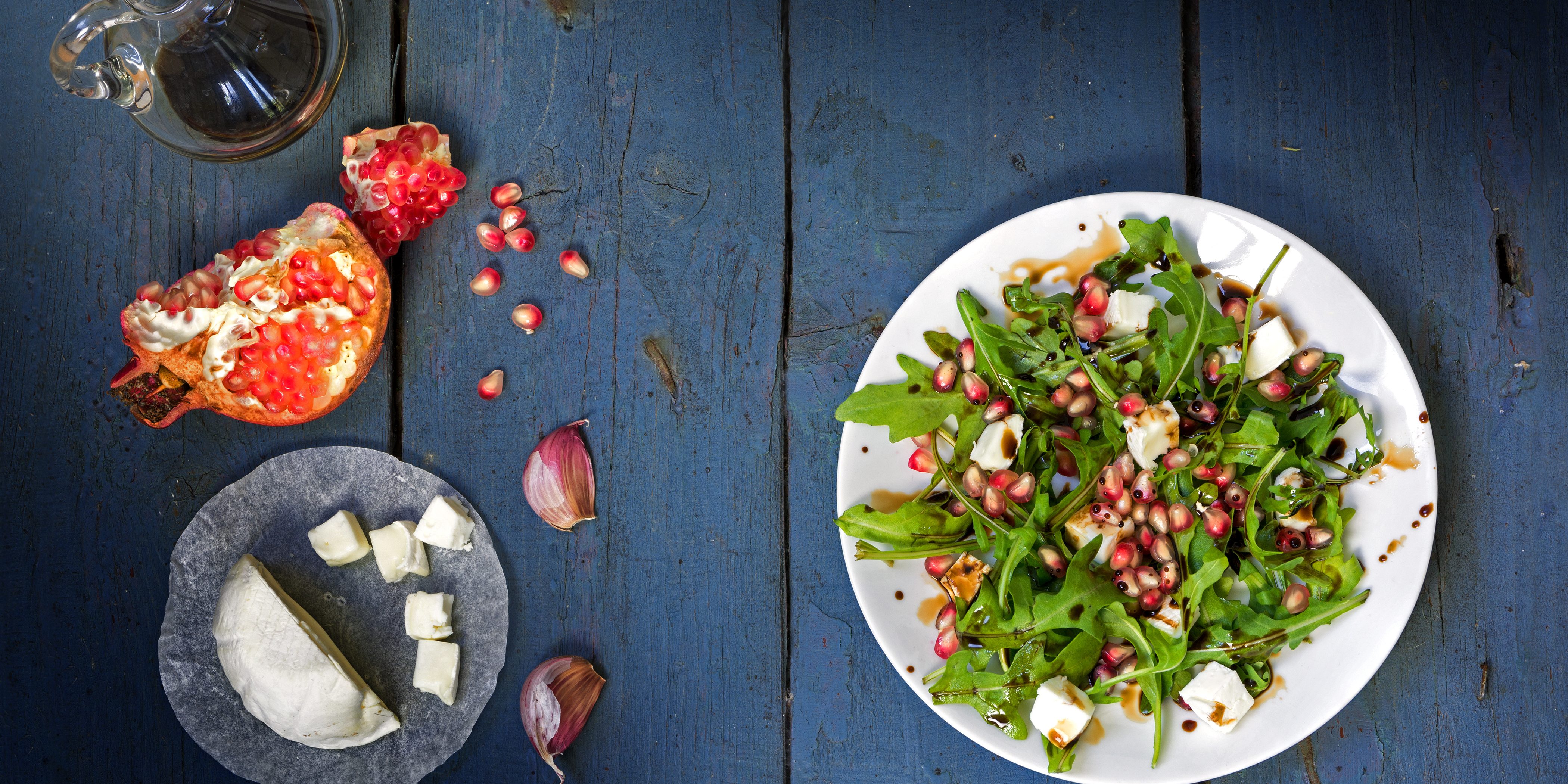 rocket salad with cheese and pomegranate on rustic wood, view fr