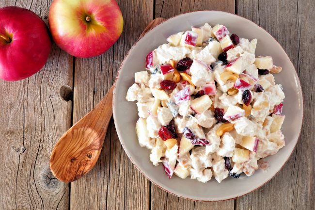 Autumn saladwith chicken, apples, nuts and cranberries, over wood